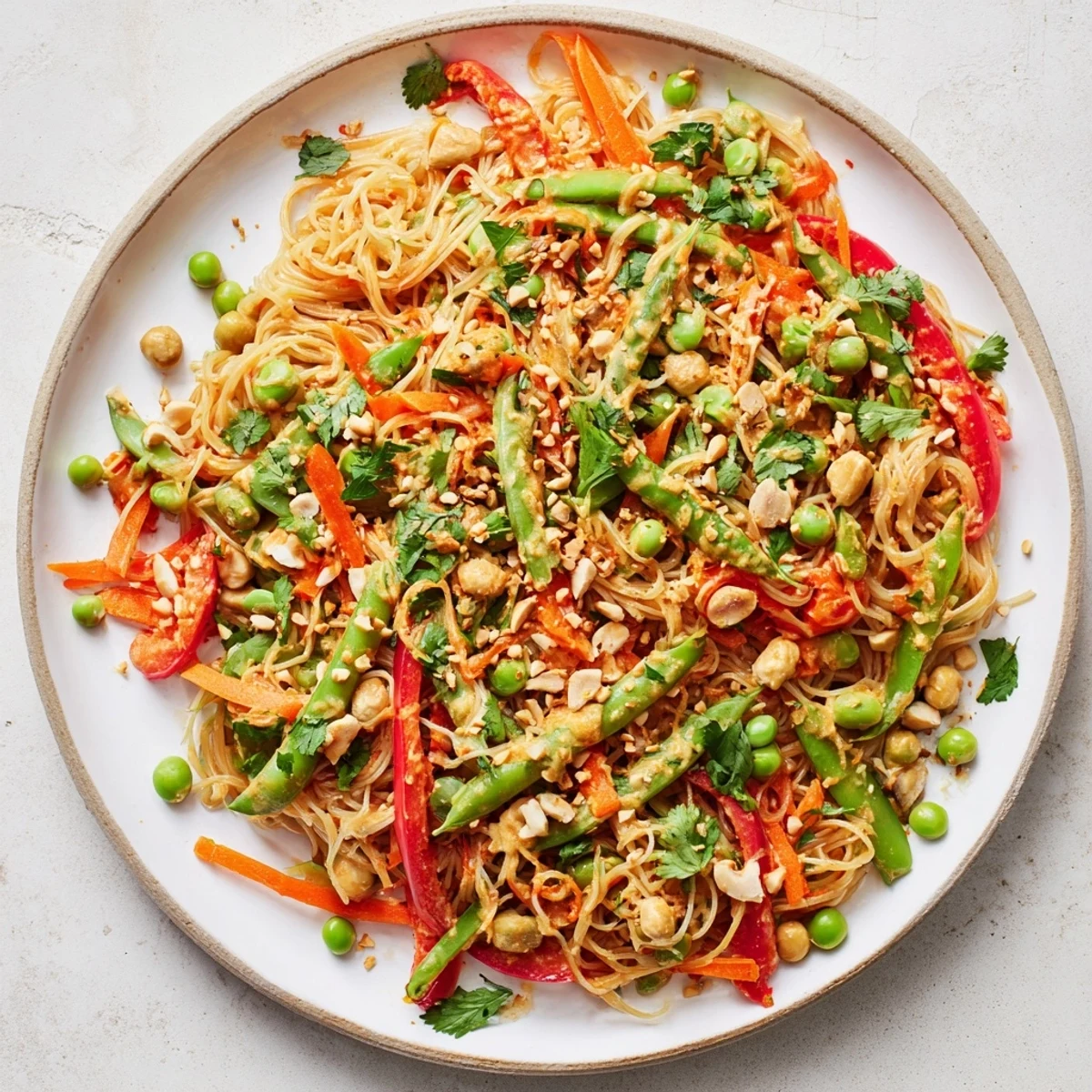 Steaming Spicy Peanut Noodle Salad, colorful with carrots and peppers, ready to serve with lime wedges.