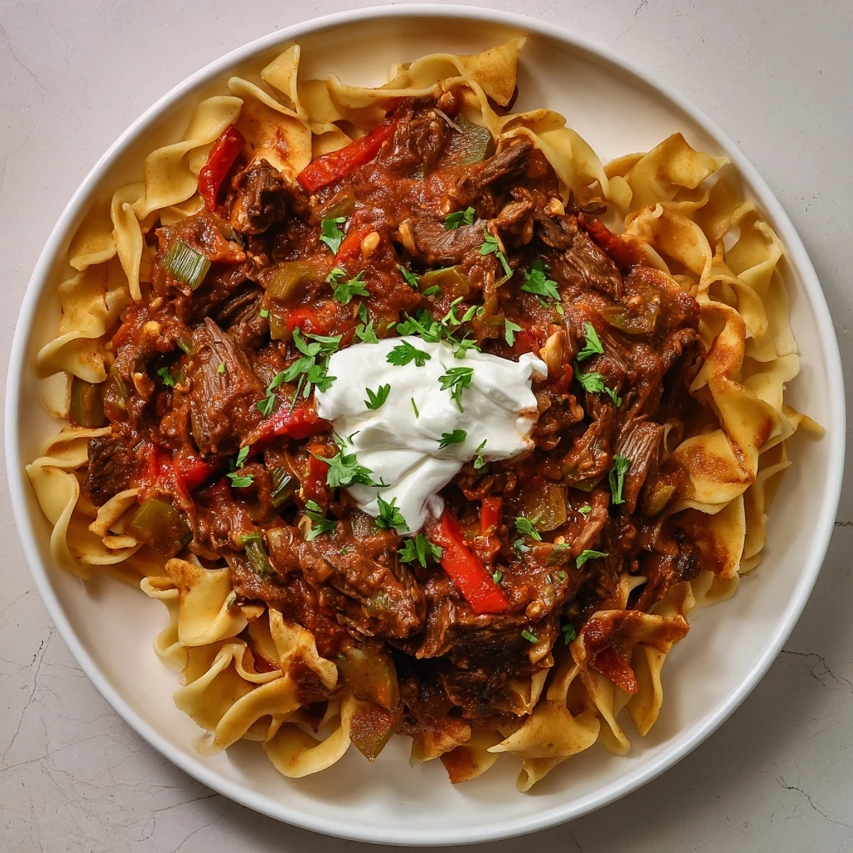 Steaming Hungarian Goulash served over fluffy egg noodles, a rustic, savory stew delight.