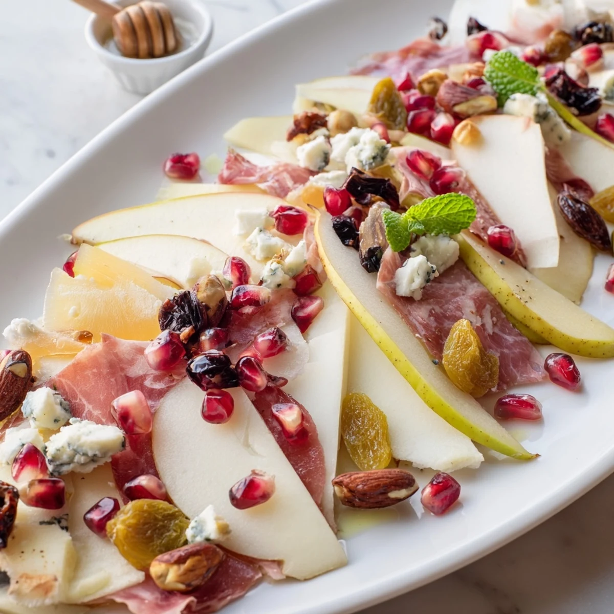 This Pomegranate Jewel Cascade displays a beautiful charcuterie board with sparkling pomegranate seeds and savory treats.