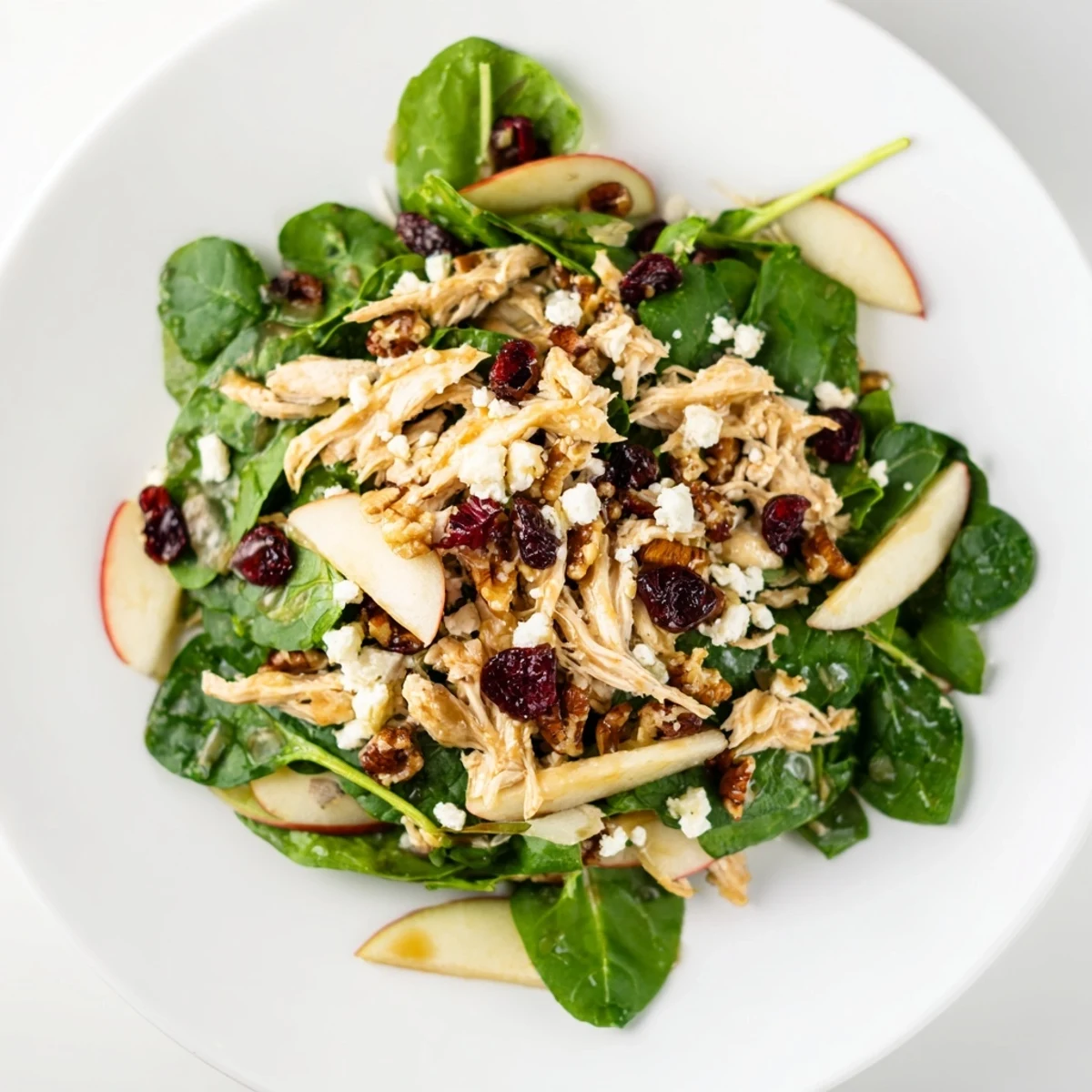 Freshly assembled Chicken and Apple Winter Salad features vibrant apples, chicken, and a drizzle of tangy dressing.