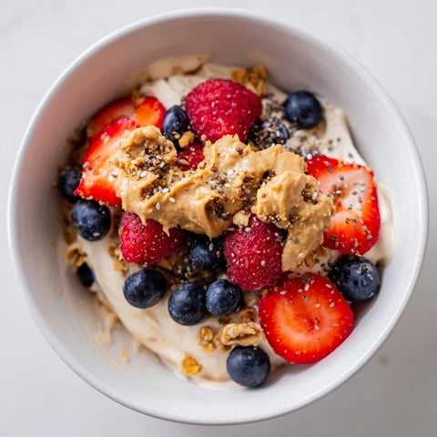 A healthy Protein Ice Cream Bowl topped with fresh berries and creamy nut butter, simply delicious!
