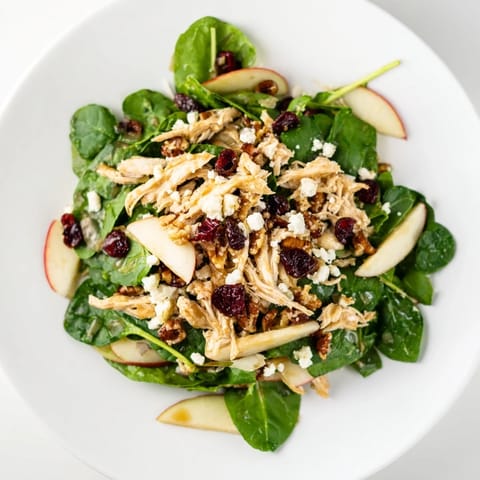 Freshly assembled Chicken and Apple Winter Salad features vibrant apples, chicken, and a drizzle of tangy dressing.