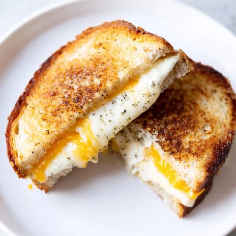 A close-up of a perfectly toasted Garlic Butter Mayo Grilled Cheese, with melted cheese pull.