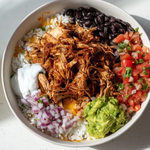 A vibrant Chipotle Burrito Bowl copycat topped with juicy carnitas and creamy queso, ready to enjoy.