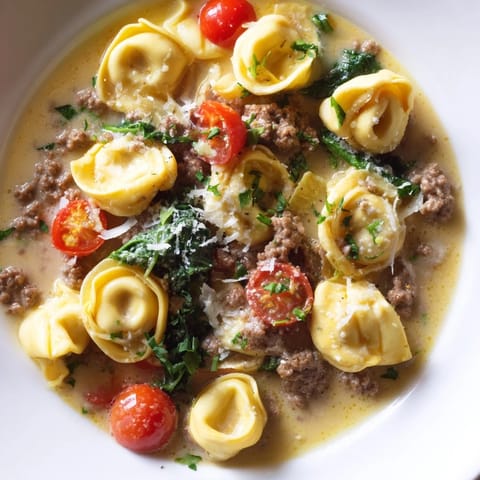 A steaming bowl of Tortellini Beef Soup garnished with fresh basil and grated Parmesan cheese.