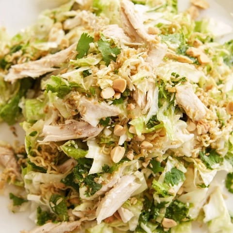 Hearty bowl of Crunchy Ramen Chicken Salad topped with almonds, scallions, and tender rotisserie chicken, served for lunch.  