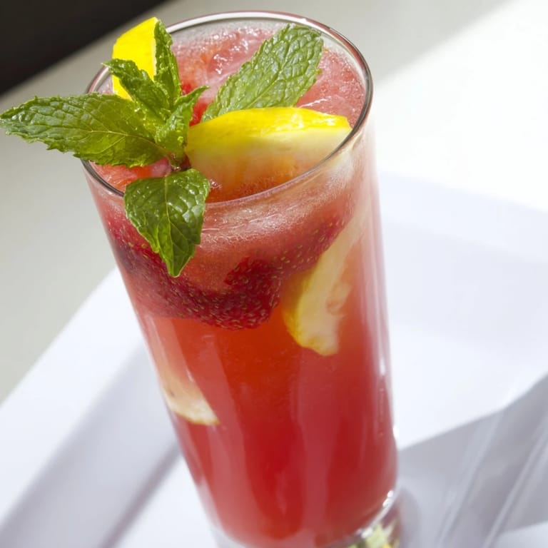 Bright pink and yellow DIY fruit refresher drinks, garnished with fresh fruit and mint.