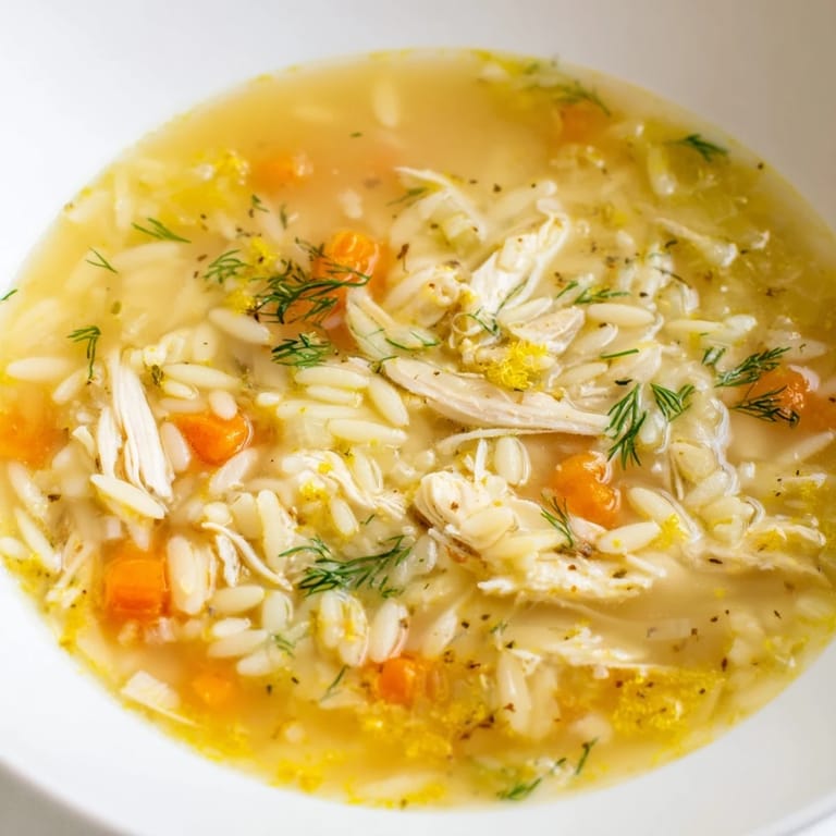 Steamy Chicken Lemon Orzo Soup in a rustic bowl with lemon zest and parsley, ready for a cozy Mediterranean-inspired dinner.