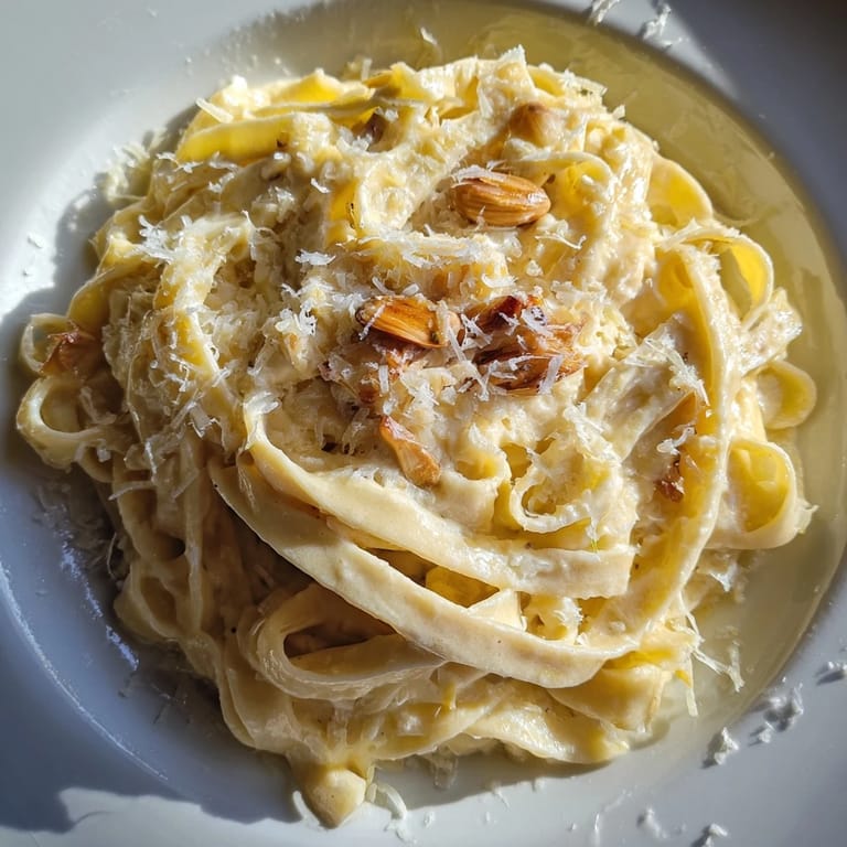 Close-up of Roasted Garlic Cream Pasta twirled on a fork, steam rising from the cheesy, velvety sauce.
