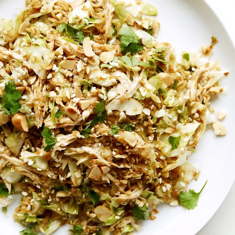 Vibrant Crunchy Ramen Chicken Salad featuring toasted sesame seeds, fresh cilantro, and crunchy noodles on a white plate.