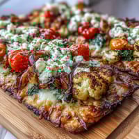 Vibrant St. Patricks Day rainbow veggie flatbread pizza with colorful vegetables arranged in festive stripes, topped with melted cheese and fresh herbs.