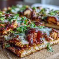 Grilled BBQ chicken flatbread pizza with melty mozzarella, red onions, and bell peppers, drizzled with smoky BBQ sauce.